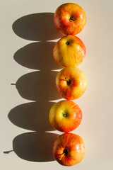 A set of apples in a row. Apples are yellow-red. Hard light.