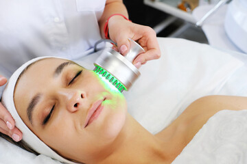 Obraz na płótnie Canvas Light infrared therapy. Cosmetology head procedure. Beauty woman face. Cosmetic salon device. Facial skin rejuvenation