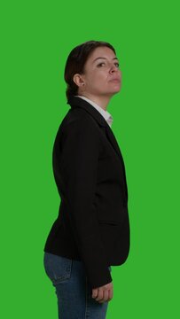 Vertical video: Profile close up of focused businesswoman standing over greenscreen backdrop, acting optimistic and confident in studio. Corporate worker wearing office suit on camera, stylish manager