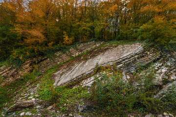 Beautiful mountain landscape in autumn under a blue sky. Textured rocks in the autumn landscape. Beautiful mountain landscape in autumn. Yellow-red foliage on the trees. Autumn view of the mountains. 