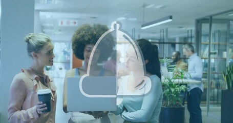 Animation of bell icon over diverse female colleagues discussing over a laptop at office - Powered by Adobe