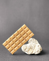 Bar of white chocolate on stone gray background. Side view. Place for text