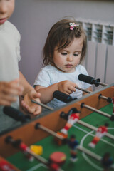 Baby girl having fun playing table football in a children's play entertainment center with her brother. Hobby and leisure