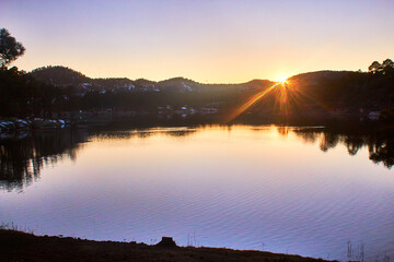 lake on sunset with sun in the horizont, mountains in the background, lake arareco in creel chihuahua 