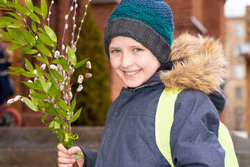 boy holding willow branches goes to church. happy schoolboy celebrating verbal or palm sunday.	