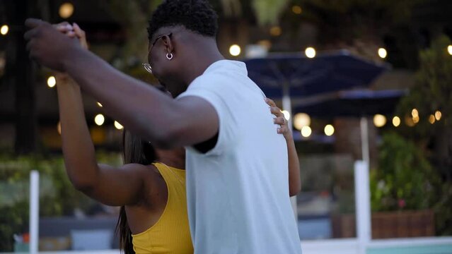 Happy young African American couple dancing outdoors in the dance floor of a Caribbean restaurant during beach holidays. 