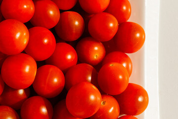 Cherry tomatoes. Cherry tomatoes in a white plate. Hard light. Bright light and shadow.
