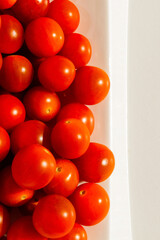 Cherry tomatoes. Cherry tomatoes in a white plate. Hard light. Bright light and shadow.