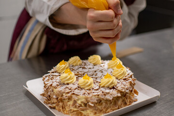 Pastry chef decorating an almond cake with sweet egg yolk