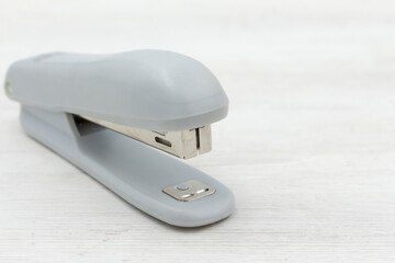 Gray stapler on white wooden background. office stationery.