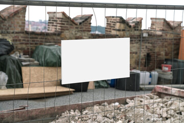 White information plate fixed on steel fence of construction site outdoor. Building renovation...