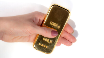 A kilogram ingot of gold in a woman's hand isolated on white background.