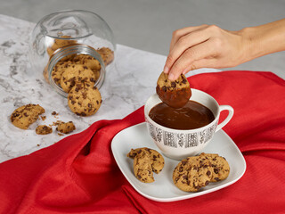 Hand picking up a chocolate cookie and cup with hot chocolate
