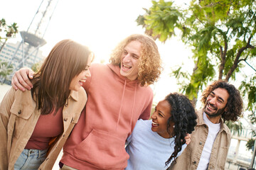 Cheerful group of friends walking and laughs outdoors in the park. Young happy people having fun. High quality photo
