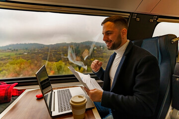 Passenger on a train is working remotely on his laptop, he has a video call meeting going over the...