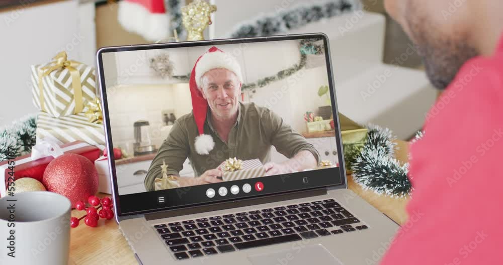 Wall mural African american man with christmas decorations having video call with caucasian man