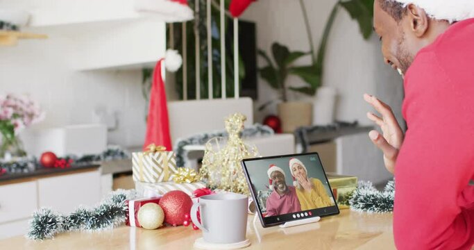 African american man with christmas decorations having video call with diverse couple