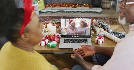 Animation of senior biracial couple on laptop video call with friends at christmas - Powered by Adobe