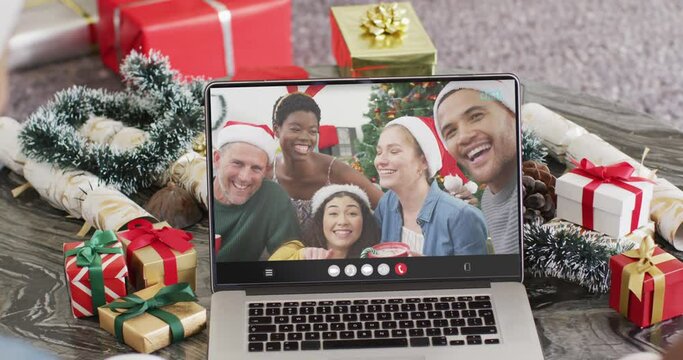 Animation of diverse friends in santa hats on laptop video call at christmas