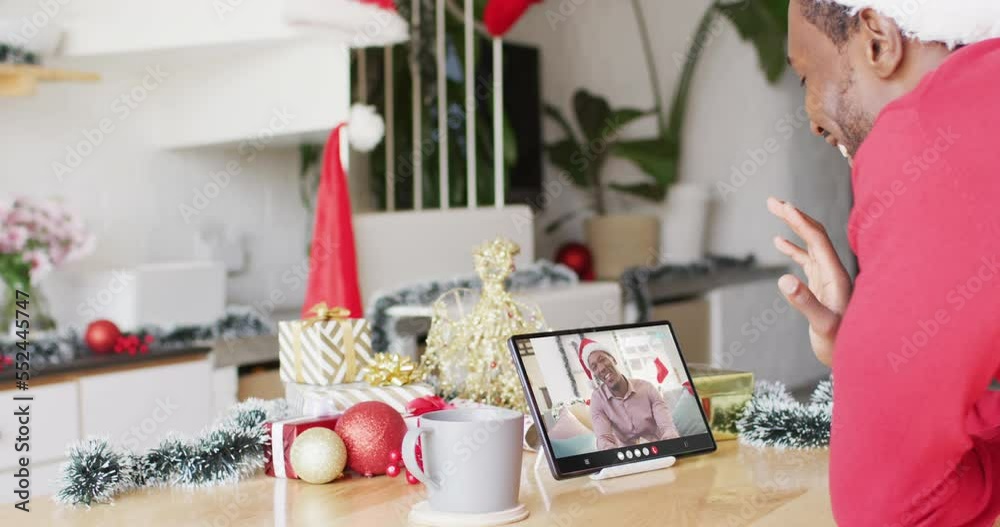 Wall mural African american man having christmas video call with african american man