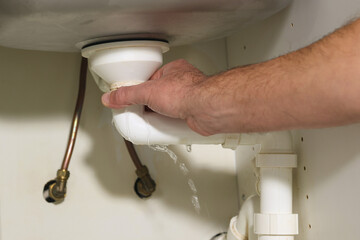 Plumber's man hand holding plumbing pipe, working on repairing broken water pipe under the sink...