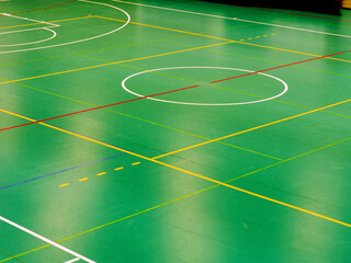 Light reflection in green indoor playfield for basketball or handball. School gym