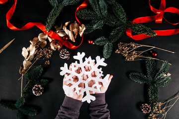 Children holding a white paper snowflake. Making your own Christmas decor. Happy holidays and New year concept.