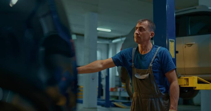 Auto mechanic lifts a car on a car lift. Car repair shop.