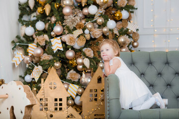 Merry christmas and happy New year! Portrait of a beautiful little one-year-old girl on the sofa in the living room. The concept of children's recreation, family and holiday.
