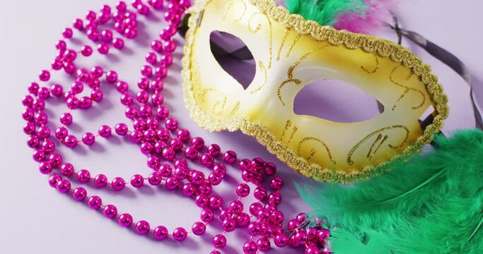 Video of carnival masquerade mask with green feathers and pink mardi gras beads