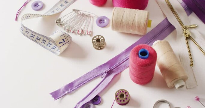 Video of tape measure, safety pins, reels of thread and zips on white background
