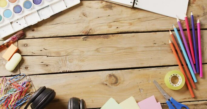 Video of paints, pencils, headphones and stationery on wooden boards with copy space