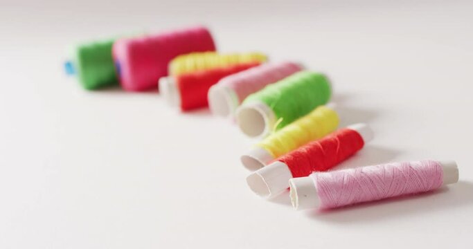 Video of spools of colourful embroidery threads in a row on white background with copy space