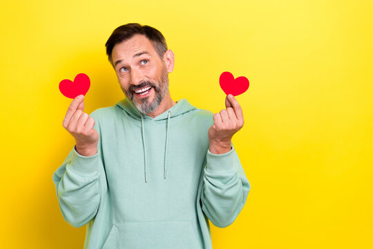 Portrait of optimistic satisfied man dressed green hoodie look empty space fingers hold paper likes isolated on yellow color background - Powered by Adobe