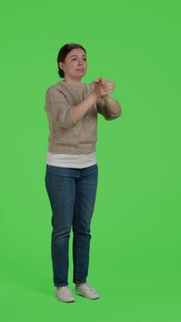 Vertical video: Side view of young adult doing standing ovation and saying congratulations in studio, applauding or clapping hands. Cheerful caucasian woman celebrating success and support