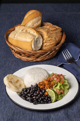 Casado, typical Costa Rican dish with rice, beans and vegetables on a table with blue tablecloth.