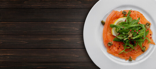 Salmon carpaccio, on a plate, with lemon , on concrete. Banner