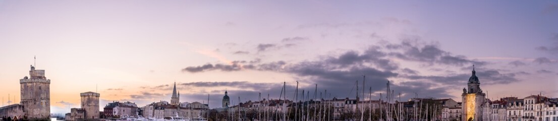 Fototapeta na wymiar La rochelle harbor at sunset. Panorama skyline. the famous towers of La Rochelle are illuminated with christmas light. banner with copy space