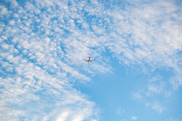 The plane flies against the background of blue clouds. Airplane takes off