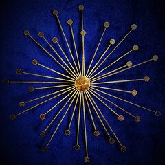 Yellow gold metal wall ornament representing the sun on a blue background. It is a wall decoration which can be interpreted as spiritual and symbolic