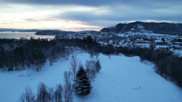 Flight toward the harbor of the coastal town of Os&oslash;yro, Bj&oslash;rnafjorden, Norway during winter. Sunset.