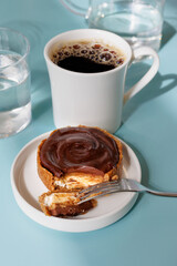 cake and black coffee in white cup for breakfast home or in cafe-restaurant. delicious and nutritious food. glass of water and on blue table, baking chocolate dessert