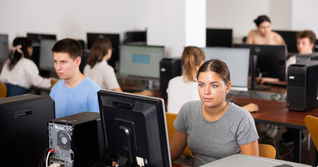 Smart female teenager learning computer science while she is using a PC in the computer classroom