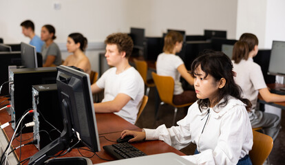 Concentrated Asian female student using PC and studying computer science in the classroom