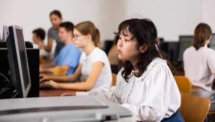 Asian girl using computer during computer sciene lesson in school.
