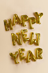 Naklejka premium Huge golden foil letter balloons spelling happy new year on beige colored seamless background