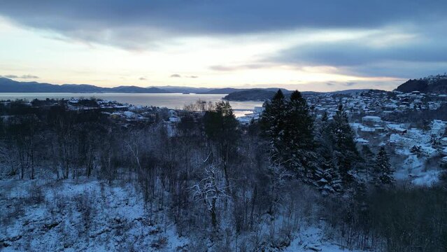 Flight toward the harbor of the coastal town of Os&oslash;yro, Bj&oslash;rnafjorden, Norway during winter. Sunset.