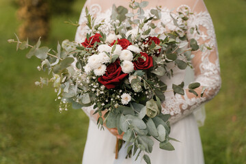 sweeping wedding bouquet with red roses in the hands of the bride