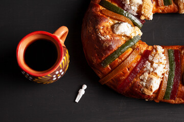 Traditional rosca de reyes and coffee on black background