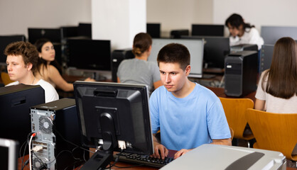 Fototapeta premium Concentrated schoolboy working with computers in classroom